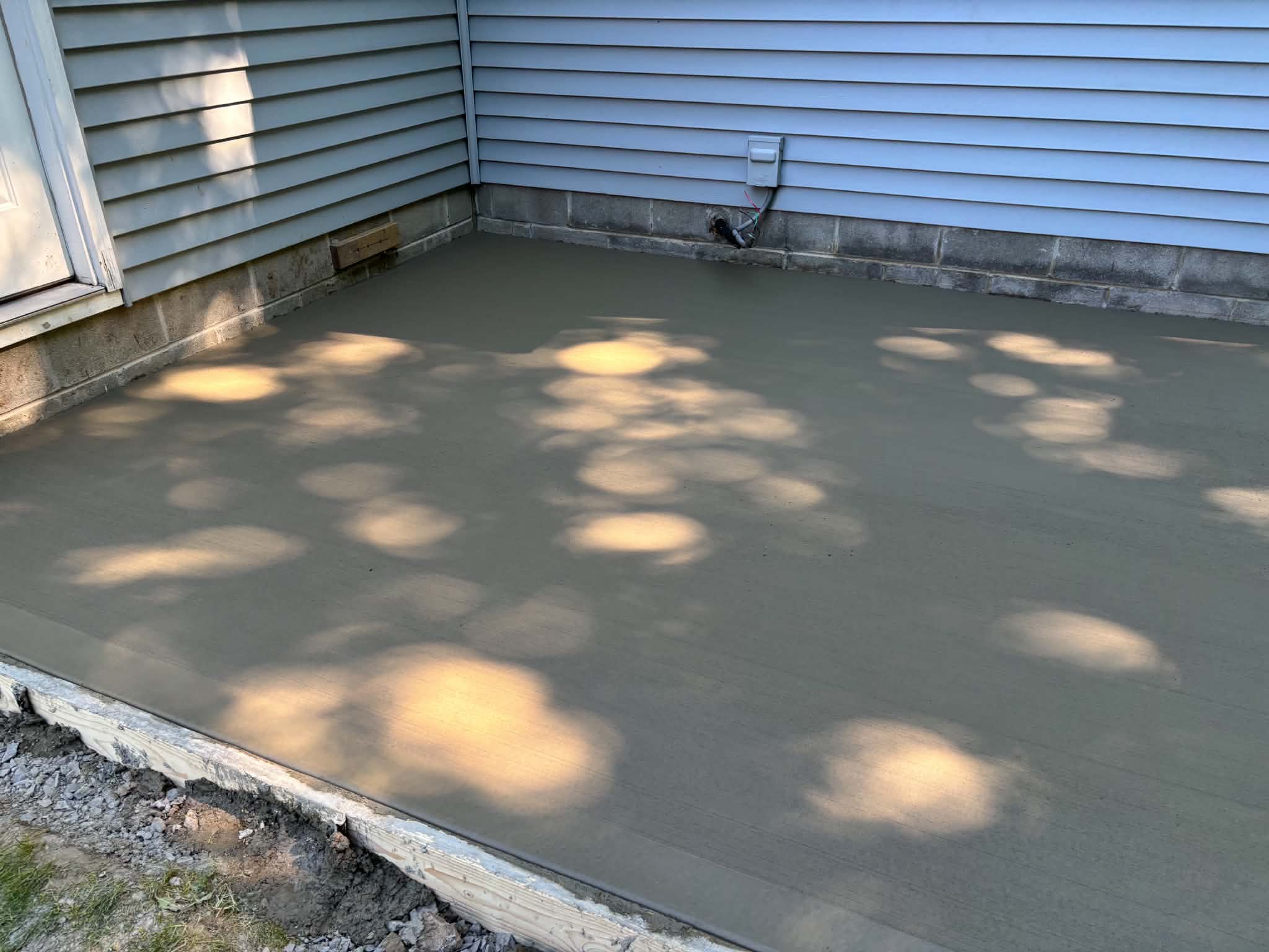 Finished broom-finish concrete pad fresh pour — Keystone Masonry concrete patio installation Rochester NY, forms still in place